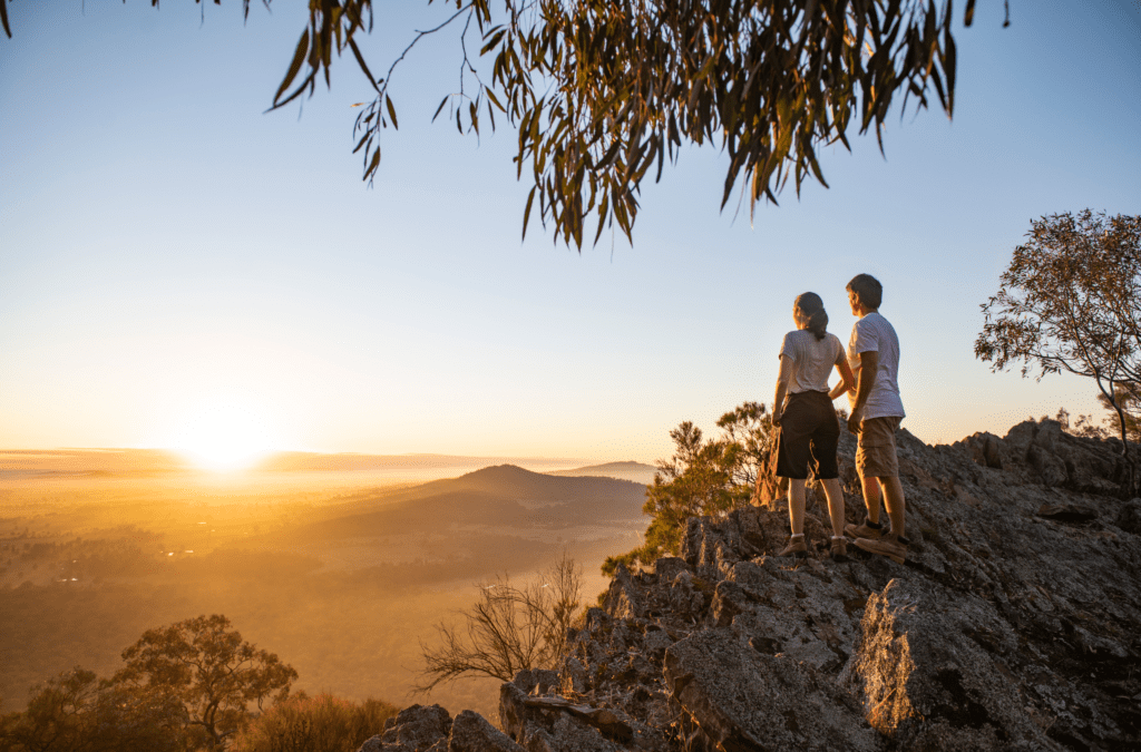 A couple stand at a look out point admiring the sunset view at the Kengal Aboriginal Place, The Rock Mature Reserve