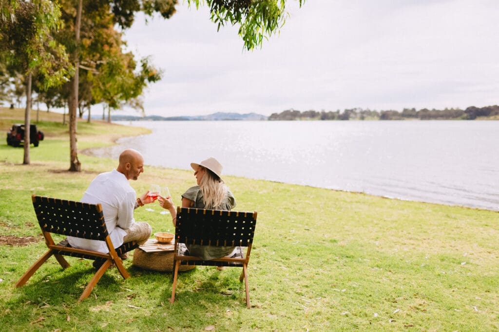 Two people sitting on chairs on the banks of Lake Hume.