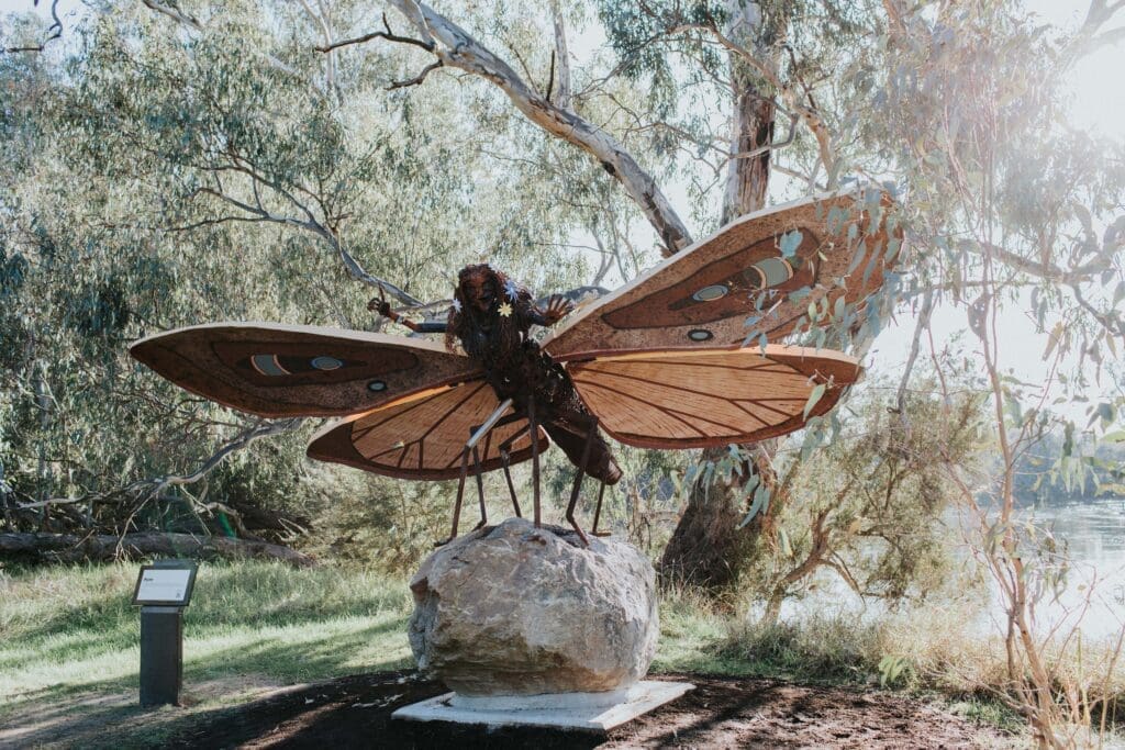A large sculpture of a moth-woman standing on top of a large rock on the Crossing Place Trail. The sculpture is named Myee by Treahna Hamm