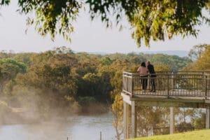 A couple stand on the viewing platfrm next to the Hume Dam Wall at Lake Hume.