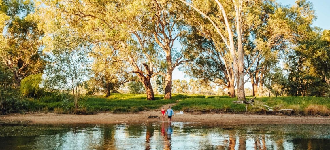 A couple are entering the water for a swim on the banks of the Murray River